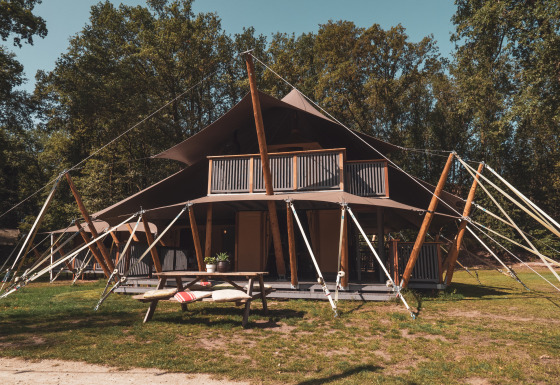 Safari tent Kings Lodge with hot tub at Sandberghe in the Netherlands, surrounded by greenery and trees.