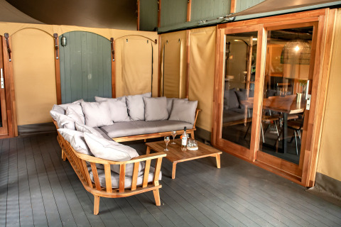 Gemütliche Sitzecke im Safari-Zelt Kings Lodge + Hot Tub bei Sandberghe, Niederlande, mit Holzmöbeln.
