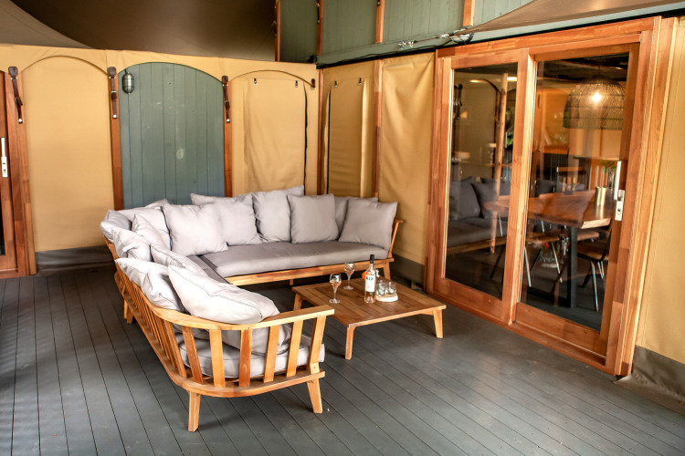 Outdoor lounge at Kings Lodge + Hot Tub, Sandberghe, Netherlands, featuring wooden sofas and cushions.