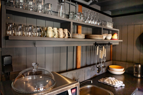 Acogedora zona de cocina con estantes abiertos, vasos y platos en Kings Lodge en Sandberghe, Países Bajos.