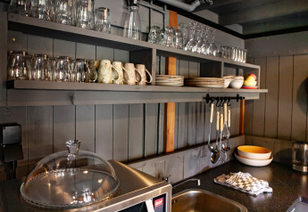 Hyggelig køkkenplads med åbne hylder, glas, tallerkener og kopper i Kings Lodge på Sandberghe, Holland.