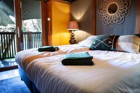 Inviting bedroom with double bed and balcony at Kings Lodge safari tent with hot tub at Sandberghe, Netherlands.