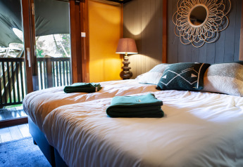 Acogedor dormitorio con cama doble en la tienda safari Kings Lodge con balcón y jacuzzi en Sandberghe, Países Bajos.