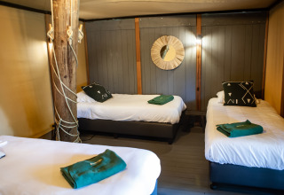 Habitación acogedora con tres camas individuales en tienda safari Kings Lodge con jacuzzi en Sandberghe, Países Bajos.
