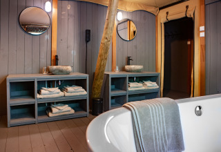 Luxury bathroom in Kings Lodge safari tent at Sandberghe, Netherlands, featuring double sinks and bathtub.