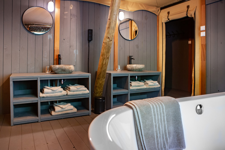 Luxury bathroom in Kings Lodge safari tent at Sandberghe, Netherlands, featuring double sinks and bathtub.