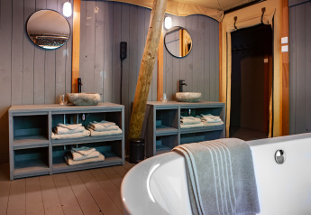 Luksuriøst badeværelse i safari-teltet Kings Lodge på Sandberghe med to håndvaske og et fritstående badekar.