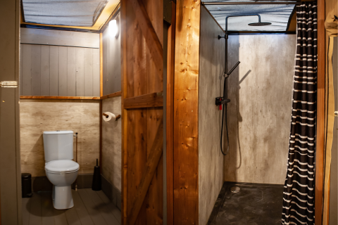Baño de tienda safari con inodoro y ducha en Kings Lodge + Hot Tub, Sandberghe, Países Bajos.