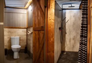 Safari tent bathroom featuring a toilet and shower at Kings Lodge + Hot Tub, Sandberghe, Netherlands.