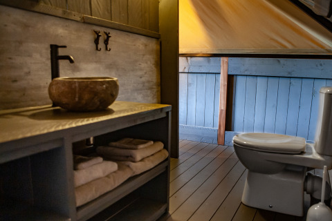 Bathroom in the Kings Lodge + Hot Tub safari tent at Sandberghe, Netherlands, with sink and toilet.
