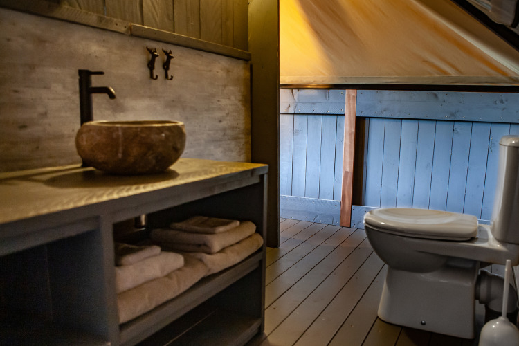 Bathroom in the Kings Lodge + Hot Tub safari tent at Sandberghe, Netherlands, with sink and toilet.