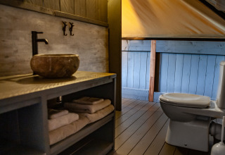 Bathroom in the Kings Lodge + Hot Tub safari tent at Sandberghe, Netherlands, with sink and toilet.