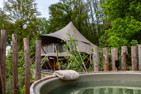 Tienda safari Kings Lodge con jacuzzi en Sandberghe, Países Bajos, rodeada de bosque y naturaleza.