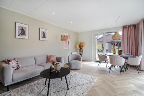 Moderne stue i Eco Lodge med lyse møbler, store vinduer, pastelfarver og elegant indretning.