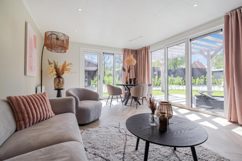 Luminoso salón en Eco Lodge con amplios ventanales, muebles modernos y vistas a un jardín privado.