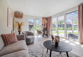 Luminoso salón en Eco Lodge con amplios ventanales, muebles modernos y vistas a un jardín privado.