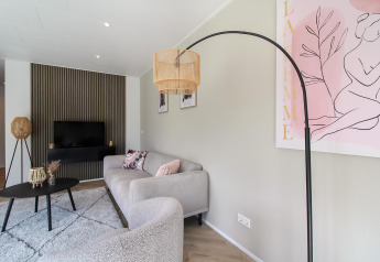 Sala de estar moderna en Eco Lodge con muebles elegantes, arte rosa en la pared y detalles de madera.