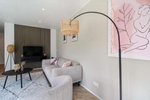 Sala de estar moderna en Eco Lodge con muebles elegantes, arte rosa en la pared y detalles de madera.