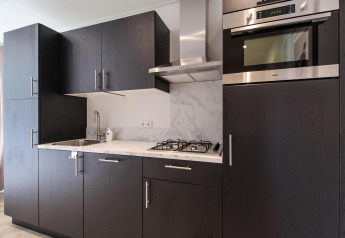 Cocina moderna en Eco Lodge con gabinetes oscuros, horno empotrado, encimera de mármol y estufa de gas.