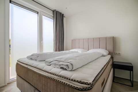 Dormitorio luminoso y moderno en Eco Lodge con cama grande, decoración minimalista y grandes ventanales.