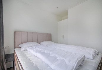 Dormitorio moderno y minimalista con cama doble, ropa de cama blanca y armario en Eco Lodge.