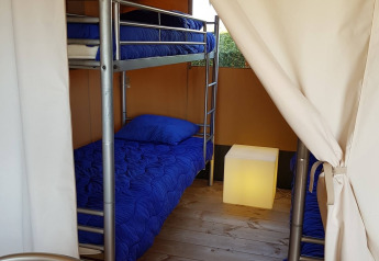 Interieur van een safaritent met stapelbedden en blauw beddengoed bij De Scherpenhof in Nederland.