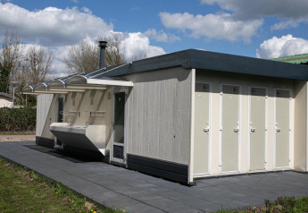 Buiten sanitairgebouw met aparte toiletten en wastafels aan de safaritent op De Scherpenhof, Nederland.