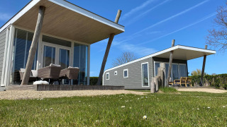 Due moderne tiny house Beach Loft con patio e sedie all'aperto al Camping Zonneweelde, Paesi Bassi.