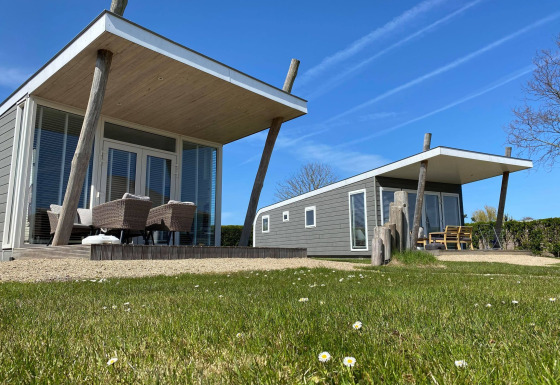 Twee moderne Beach Loft tiny houses met terras en tuinstoelen op Camping Zonneweelde in Nederland.