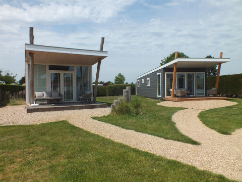 Due moderne tiny house Beach Loft al Camping Zonneweelde nei Paesi Bassi, circondate da vialetti e prato.