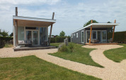 Due moderne tiny house Beach Loft al Camping Zonneweelde nei Paesi Bassi, circondate da vialetti e prato.