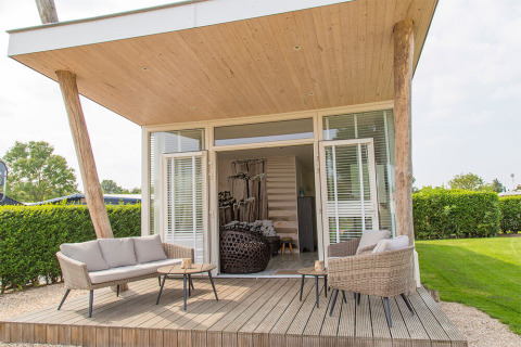 Terrazza esterna della tiny house Beach Loft al Camping Zonneweelde, Paesi Bassi, con area relax.