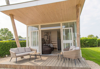 Terrazza esterna della tiny house Beach Loft al Camping Zonneweelde, Paesi Bassi, con area relax.