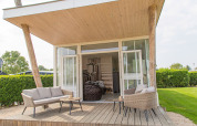 Terrazza esterna della tiny house Beach Loft al Camping Zonneweelde, Paesi Bassi, con area relax.