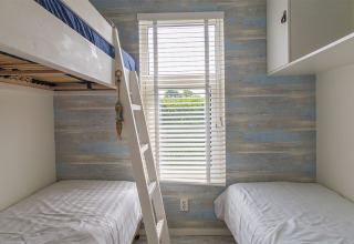 Habitación con litera y camas individuales en Beach Loft, Camping Zonneweelde, Países Bajos, luz natural.