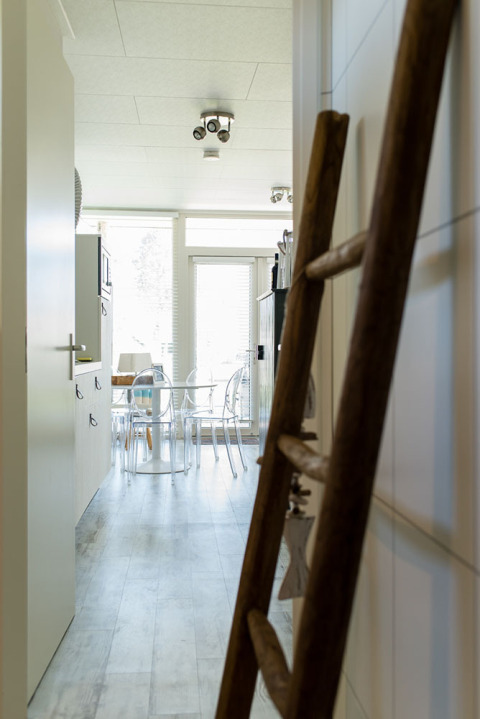 Kikker gennem en entré med træstige til et køkken og spiseplads i Beach Loft, Camping Zonneweelde, Holland.