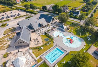Vue aérienne d’un site de glamping avec piscine, pataugeoire, aire de jeux et espaces verts.