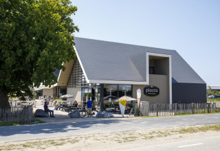 Alojamiento glamping moderno con edificio de madera elegante y asientos al aire libre bajo el sol claro.