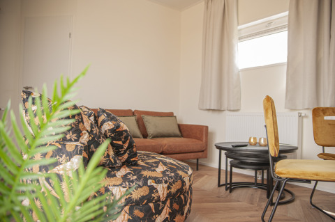 Modern eingerichtetes Wohnzimmer in der Dune Lodge de Luxe auf Camping Zonneweelde, Niederlande, mit gemütlicher Atmosphäre.