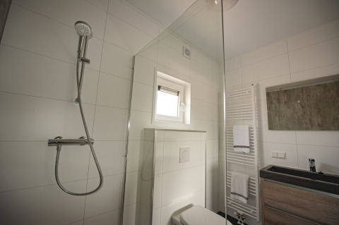 Modern ingerichte badkamer met douche, toilet en handdoeken in Dune Lodge de Luxe op Camping Zonneweelde.