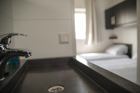 Modernes Waschbecken mit Blick auf ein Schlafzimmer in der Dune Lodge de Luxe, Camping Zonneweelde, Niederlande.