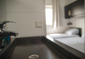 Modern wastafel op Dune Lodge de Luxe met zicht op een lichte slaapkamer, Camping Zonneweelde, Nederland.