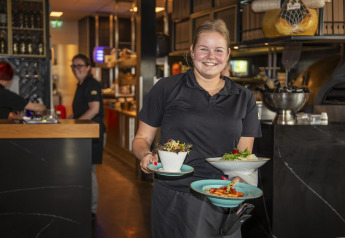 Kellnerin lächelt mit Speisen im Dune Lodge de Luxe bei Camping Zonneweelde, Niederlande, Restaurant.