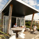 Famille détendue sur la terrasse du Beach Loft + Wellness au Camping Zonneweelde, Pays-Bas, journée ensoleillée.