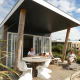 Familie genießt die Sonne auf der Terrasse des Beach Loft + Wellness am Camping Zonneweelde, Niederlande.