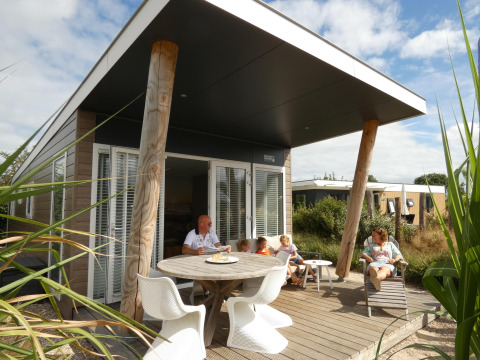 Famiglia che si rilassa sulla terrazza del Beach Loft + Wellness al Camping Zonneweelde nei Paesi Bassi.