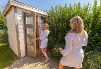 Two women in robes outside a sauna at Beach Loft + Wellness, Camping Zonneweelde in the Netherlands.