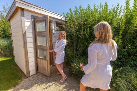 Twee vrouwen in badjas buiten een sauna aan Beach Loft + Wellness, Camping Zonneweelde, Nederland.