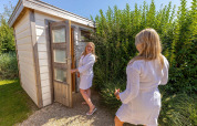 Twee vrouwen in badjassen buiten een sauna bij Beach Loft + Wellness, Camping Zonneweelde, Nederland.