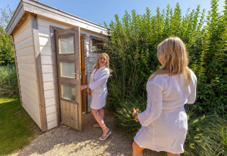 Twee vrouwen in badjas buiten een sauna aan Beach Loft + Wellness, Camping Zonneweelde, Nederland.
